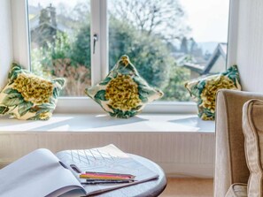 A room with a window sill, a chair, and a table with a sketchbook and colored pencils. - 2 Bed in Ambleside (oc-87180) (Ambleside)