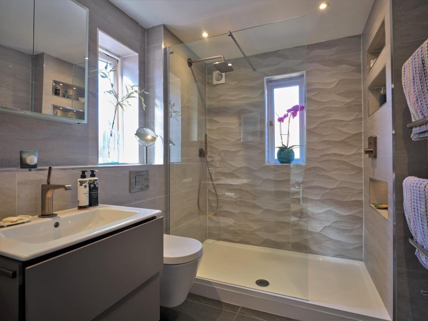A modern bathroom with a glass-enclosed shower, a toilet, and a sink.