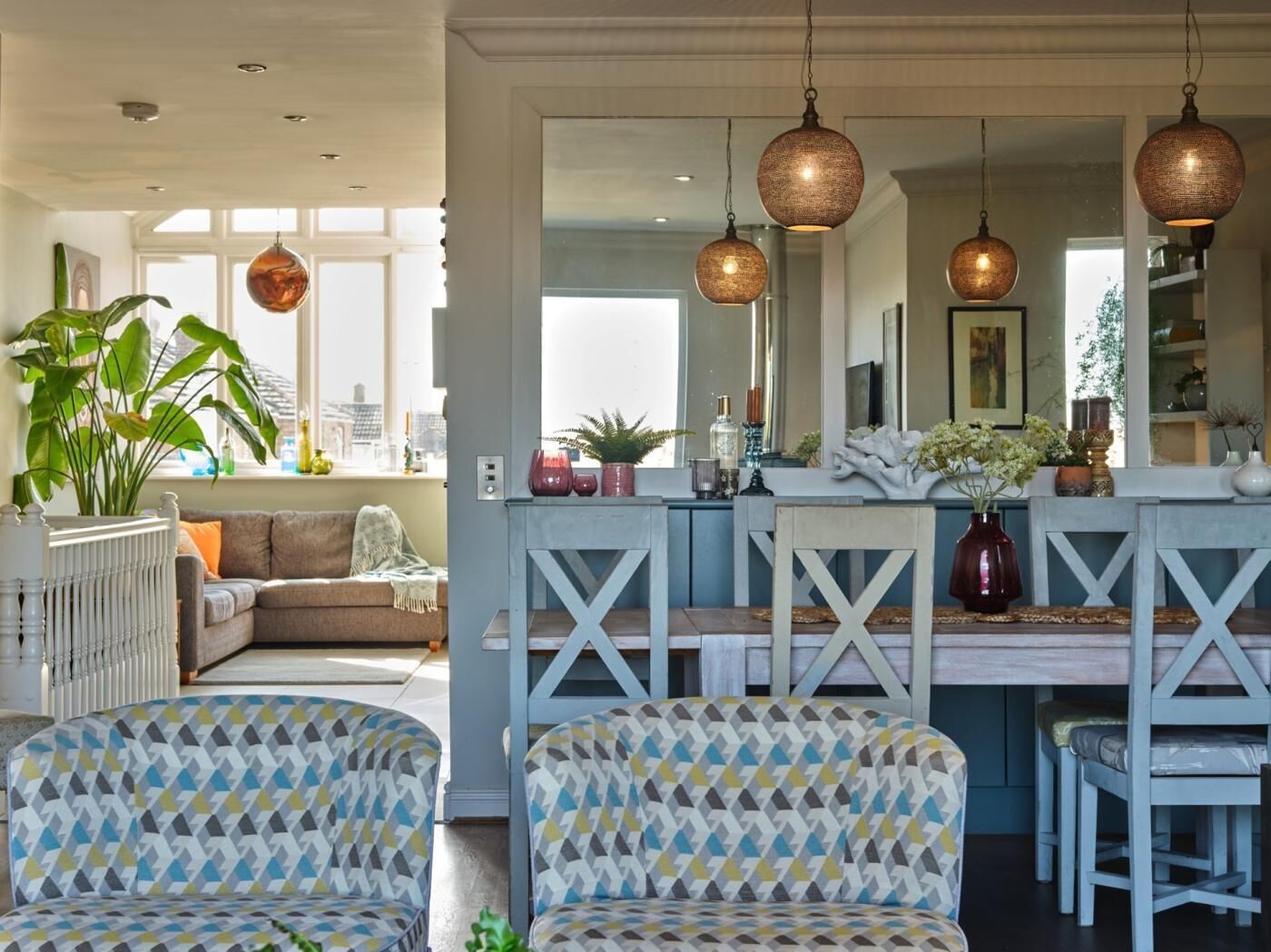 Un salon moderne avec des fauteuils à motifs, un canapé et un coin repas doté d’un bar.