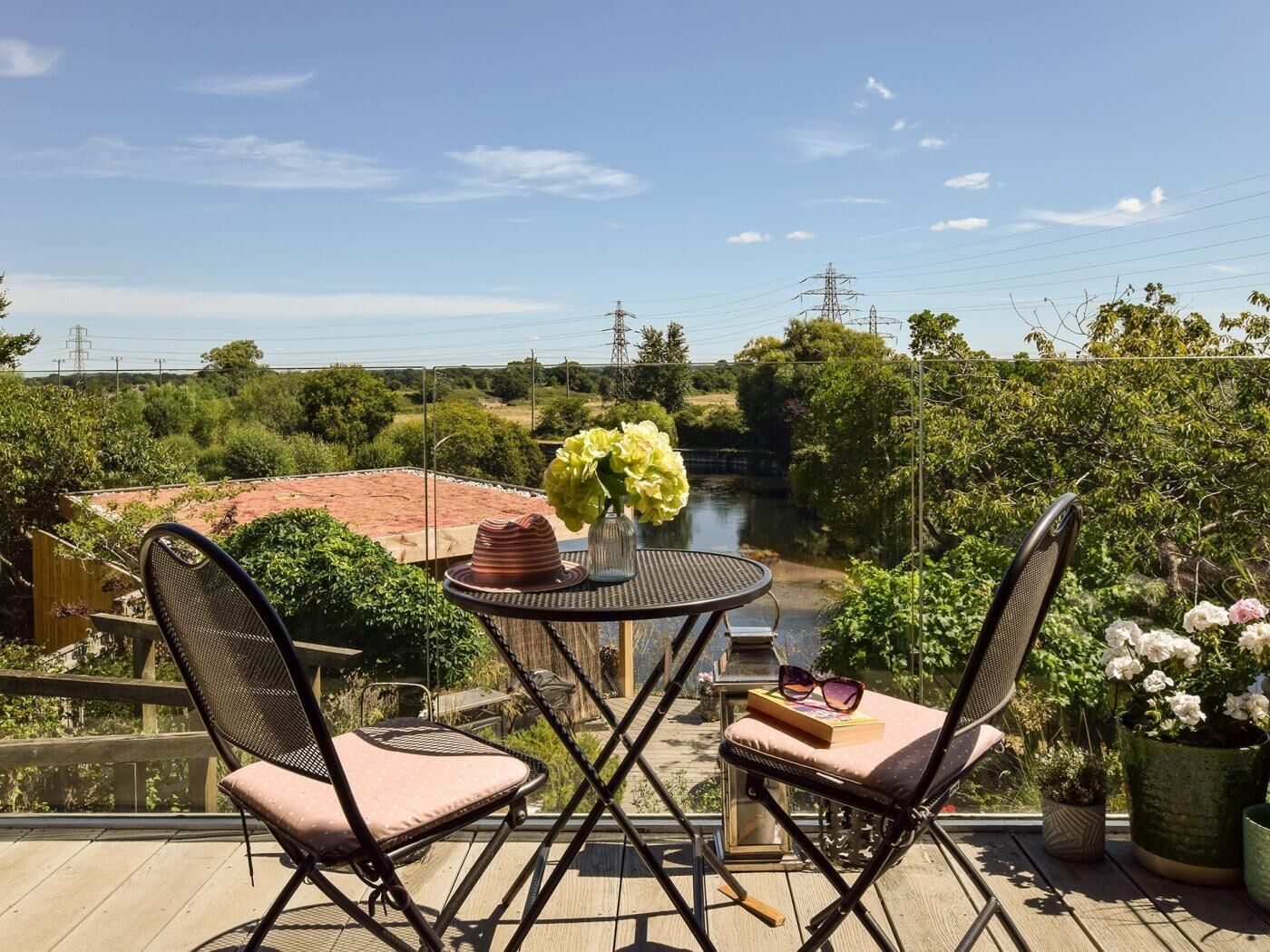 A balcony with two chairs, a small round table, and a vase with flowers.