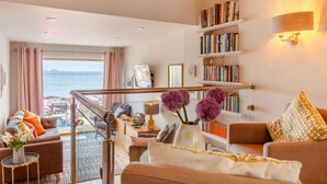 Un salon moderne avec vue sur la mer, une bibliothèque et un escalier.