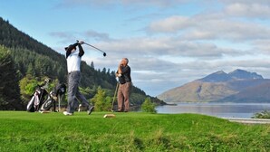 A golf course with a lake and mountains in the background.