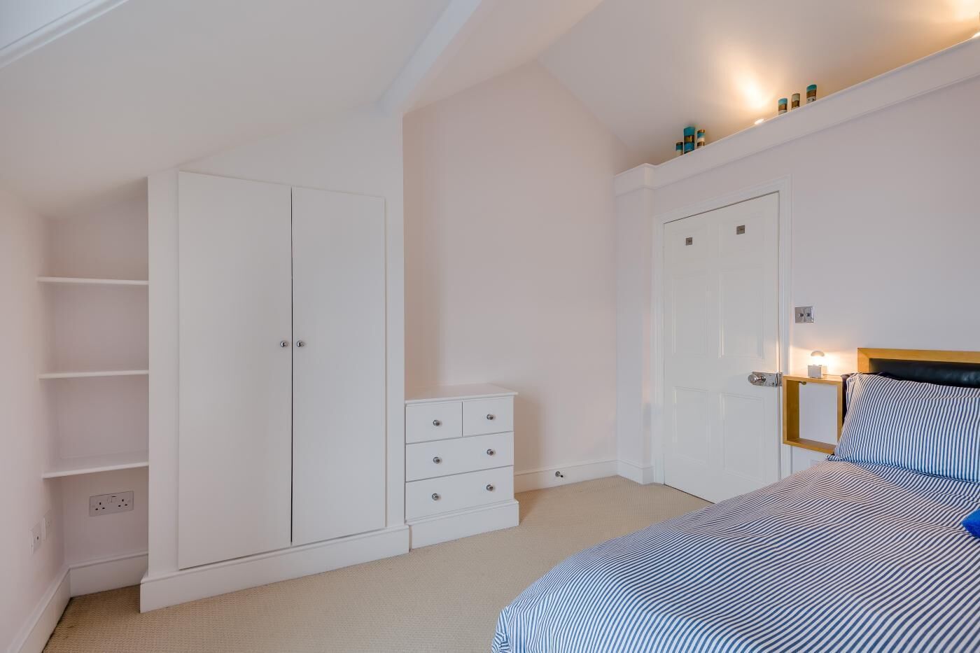 A bedroom with a bed, a wardrobe, a dresser, and a door.