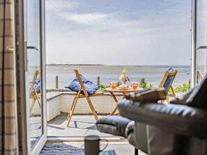 A balcony with a view of the sea, a table with drinks and pastries, and two easels. - 2 Bed in Aberdyfi (oc-dy011) (Aberdovey)