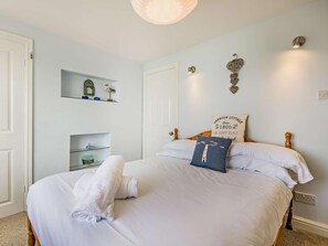 A neatly made bed with a white towel, a decorative pillow, and a sign on the headboard. - 2 Bed in Aberdyfi (oc-dy011) (Aberdovey)