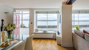 Una cocina moderna con vistas al mar, un comedor con mesa y sillas, y una sala de estar con sofá.