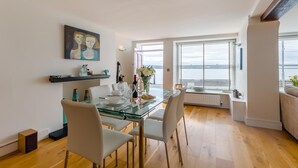 Un comedor moderno con una mesa de vidrio, sillas blancas y vistas al mar a través de amplios ventanales.