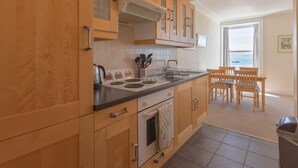Una cocina con armarios de madera, una estufa y un comedor con mesa y sillas.