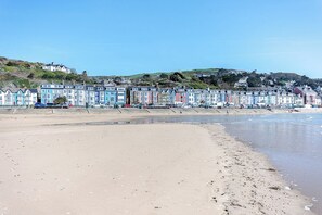 A beach with colorful houses in the background. - 5 Bed in Aberdyfi (oc-dy026) (Aberdovey)