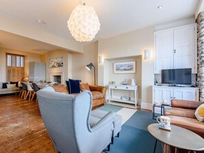 A modern living room with a sofa, armchair, and a television. - 5 Bed in Aberdyfi (oc-dy026) (Aberdovey)