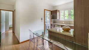 Cozinha moderna com mesa de vidro, armários de madeira e vista para o exterior.