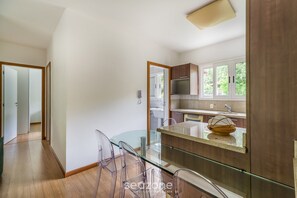 Eine moderne Küche mit einem Glastisch, Holzschränken und Blick ins Freie.