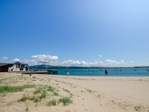 Ein Strand mit einem Gebäude, einem Steg und Booten im Wasser.