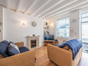 Ein modernes Wohnzimmer mit Kamin, Fernseher und einem großen Fenster mit Jalousien.