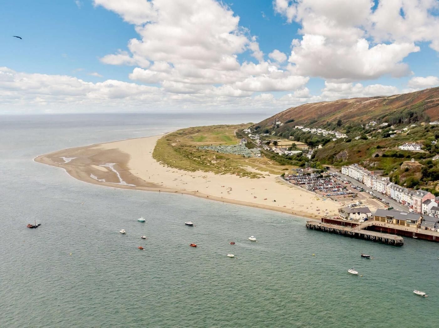 A coastal town with a beach, boats, and a pier.