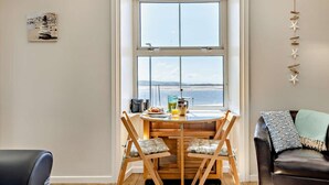 Ein Essbereich mit Tisch, Stühlen und Blick durch ein großes Fenster.