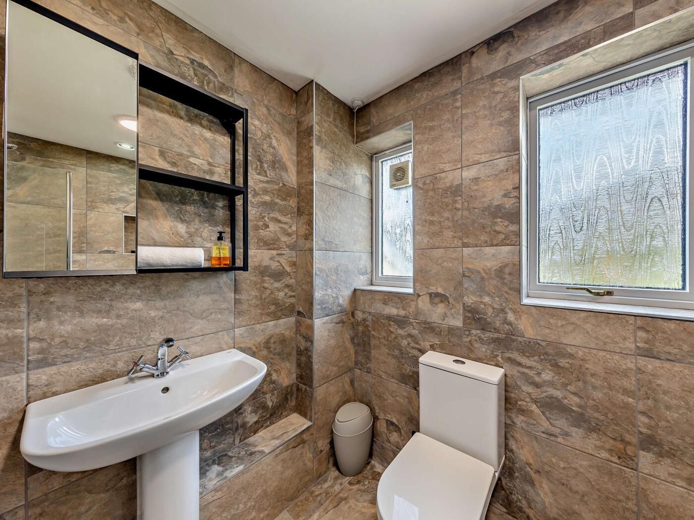 Ein Badezimmer mit Waschbecken, Spiegel, Toilette und Fenster.