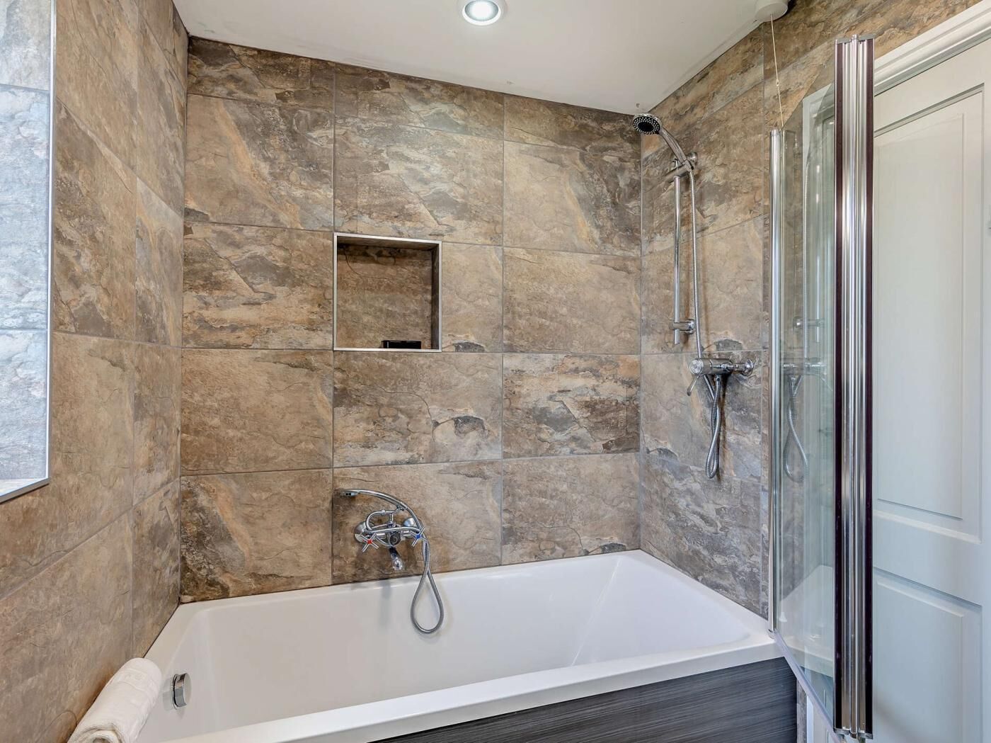 A modern bathroom with a bathtub, shower, and a glass-enclosed shower stall.