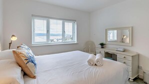 A hotel room with a bed, a desk, a chair, a window with blinds, and a ceiling light. - 3 Bed in Aberdyfi (oc-dy048) (Aberdovey)
