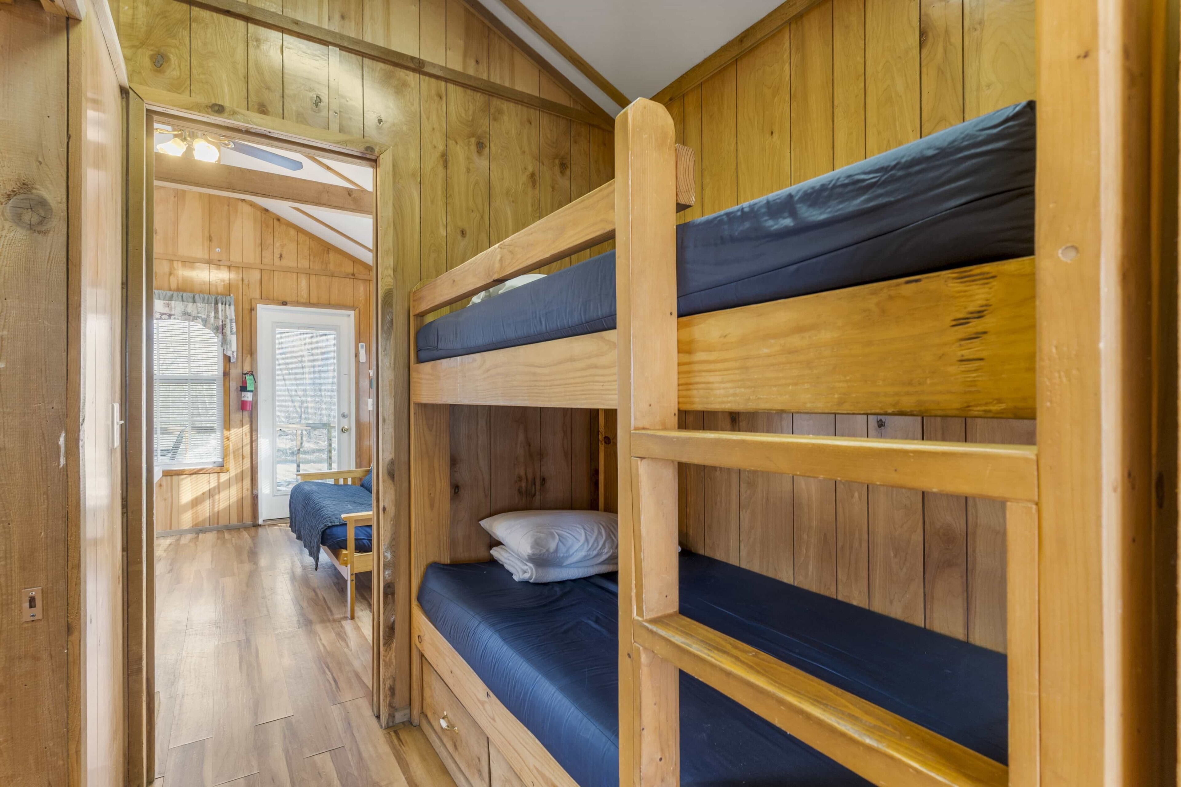 Un interno in legno con letti a castello, una porta e una finestra.