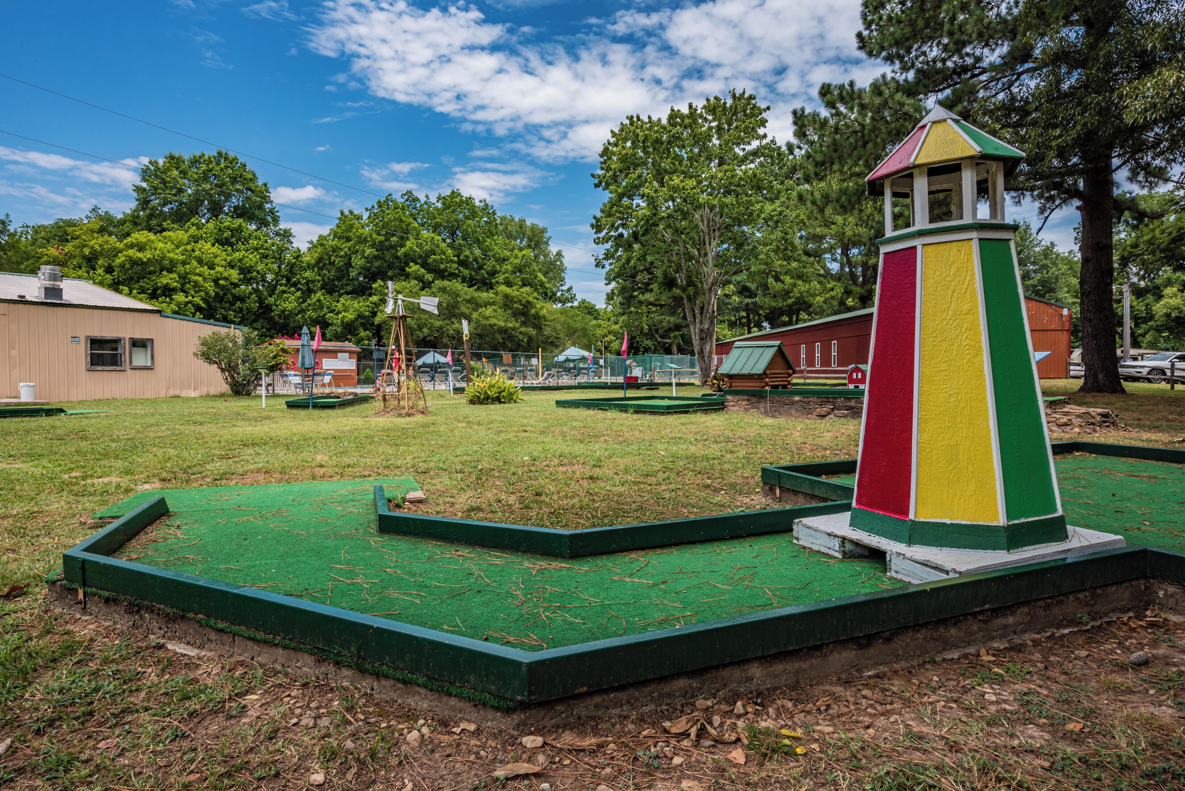 Un parcours de minigolf doté d’une surface de jeu verdoyante et d’une structure en forme de tour aux couleurs vives.