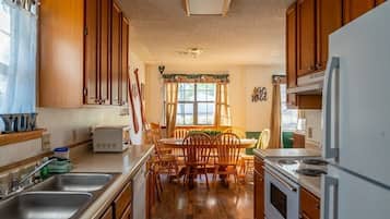 A kitchen with wooden cabinets, a dining table with chairs, a refrigerator, and a microwave.
