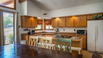 A kitchen with wooden cabinets, a dining table with chairs, a refrigerator, and a microwave.