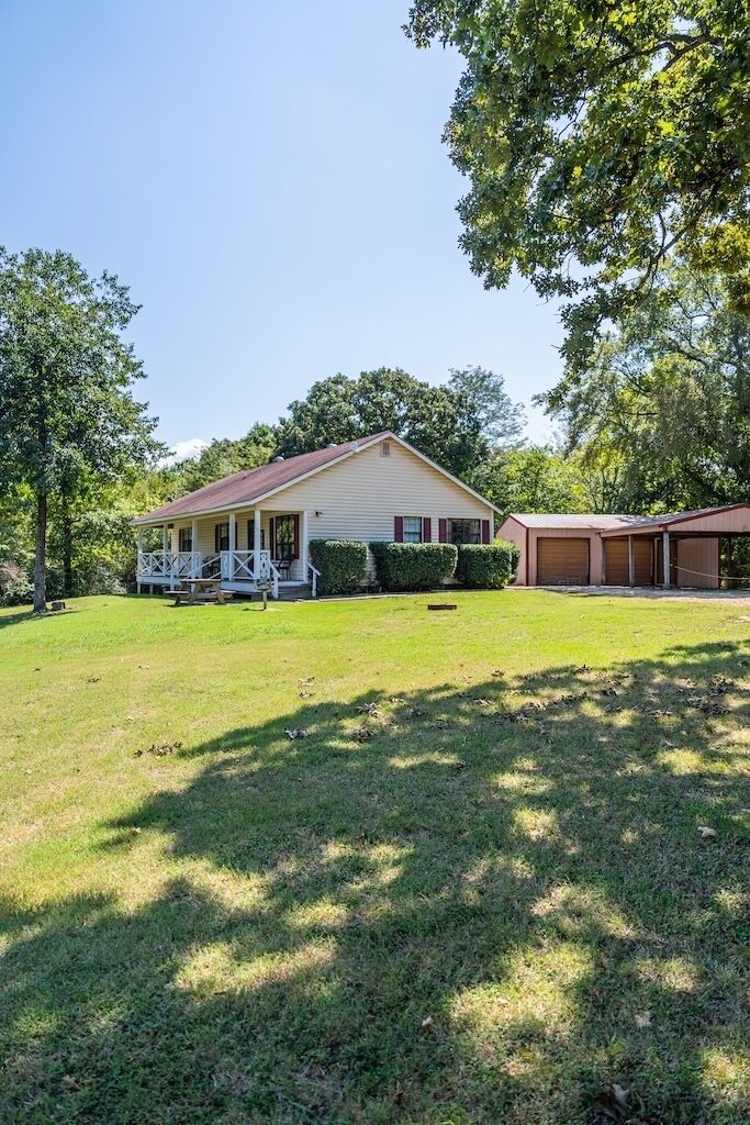 A single-story house with a porch, a garage, and a well-maintained lawn.