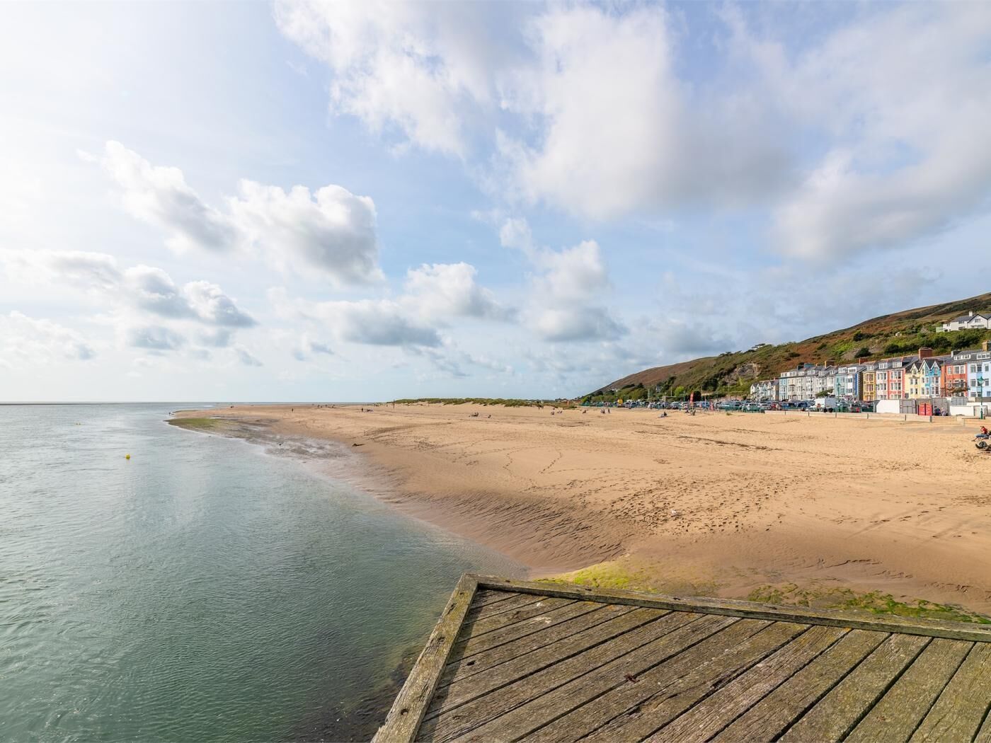 A beach with a wooden boardwalk leading to colorful buildings.