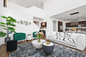 Ein modernes Wohnzimmer mit einer Couch, einem grünen Sessel, einem Couchtisch und einer Topfpflanze.