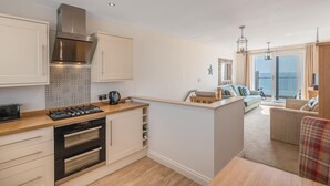 A modern kitchen with built-in appliances, a dining area with a view, and a cozy seating space. - 2 Bed in Tywyn (oc-dy052) (Tywyn)