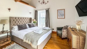 A bedroom with a large bed, a wooden ceiling, a chandelier, a desk, and a chair. - 3 Bed in Matlock (oc-86482) (Hackney)
