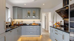 Una cucina moderna con mobili grigi, un piano di lavoro nero e un pavimento in legno.