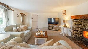 A cozy living room with a sofa, a coffee table with tea and pastries, a television, a fireplace, and a stone wall. - 2 Bed in Umberleigh (oc-86611) (Cobbaton)