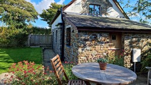 A stone cottage with a sloped roof, a wooden door, and a small window. - 1 Bed in Bideford (oc-86571) (Hartland)