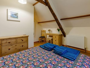 Ein Schlafzimmer mit einem Bett, einem Schminktisch, einem Schreibtisch, einem Stuhl, einer Heizung und einem gerahmten Bild an der Wand.