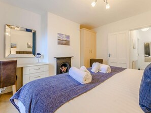 A bedroom with a bed, a dresser, a mirror, a fireplace, and a door. - 1 Bed in Keswick (oc-86560) (Keswick)