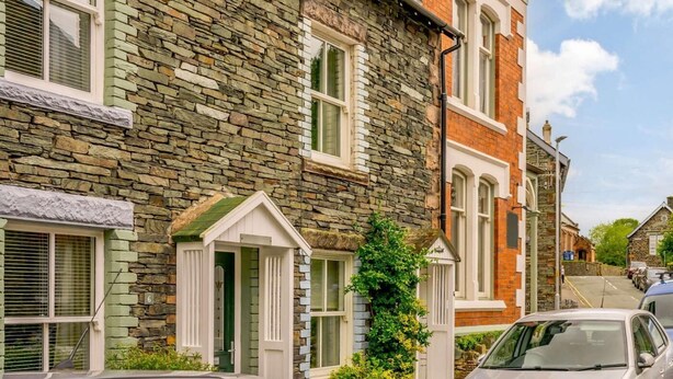 A row of townhouses with stone facades, white window frames, and a car parked in front. - 1 Bed in Keswick (oc-86560) (Keswick)