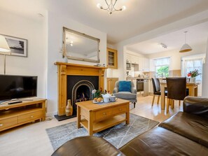 A living room with a fireplace, a television, a sofa, and a dining area with chairs and a table. - 1 Bed in Keswick (oc-86560) (Keswick)