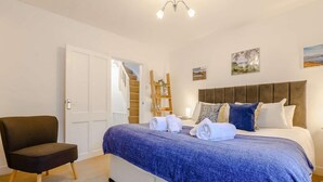 A bedroom with a bed, a chair, a door, and a staircase. - 1 Bed in Keswick (oc-86560) (Keswick)