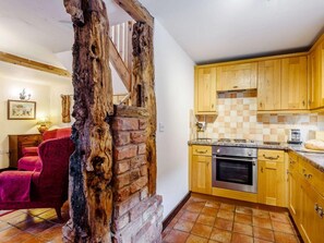 A kitchen with wooden cabinets, a brick wall, and a red chair. - 2 Bed in Shrewsbury (oc-86590) (Leighton)