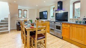Una cucina moderna con mobili in legno, forno integrato e zona pranzo con tavolo e sedie in legno.