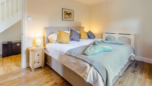 Una camera da letto con un letto, un comodino, una lampada e un quadro appeso al muro.