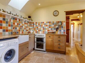 A compact kitchen with a washing machine, oven, and a tiled backsplash. - 2 Bed in South Molton (oc-86642) (Knowstone)