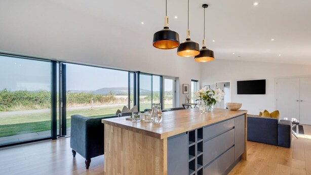 Una cocina moderna con una isla grande, ventanas amplias y un televisor de pantalla plana.