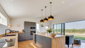 Una cocina moderna con una isla central, un comedor con vistas y un amplio ventanal.