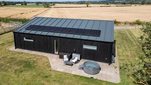 Un edificio moderno con techo plano, paneles solares, bañera de hidromasaje y zona de patio.