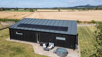 A modern building with a flat roof, solar panels, a hot tub, and a patio area.