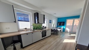 Eine moderne Küche mit Backofen, ein Essbereich mit Tisch und Stühlen sowie ein großes Fenster für natürliches Licht.