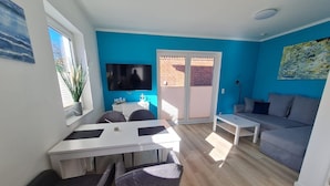 Ein modernes Wohnzimmer mit grauem Sofa, einem weißen Couchtisch und einem Essbereich mit Tisch und Stühlen.